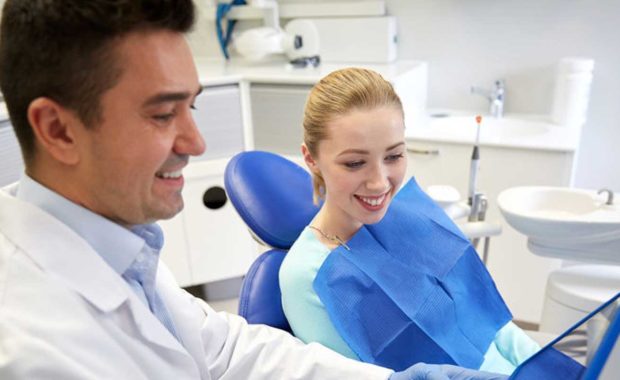 Dentist educating one of his patients by showing her his website where he used content marketing to create an article on how to properly brush your teeth