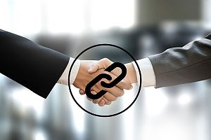 an SEO backlinking concept image showing two businessmen shaking hands with a chain link graphic over top of the handshake