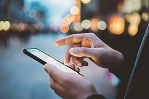 a man using his smartphone to post to his social media and increase website traffic