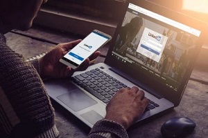 man using linkedin on mobile and laptop